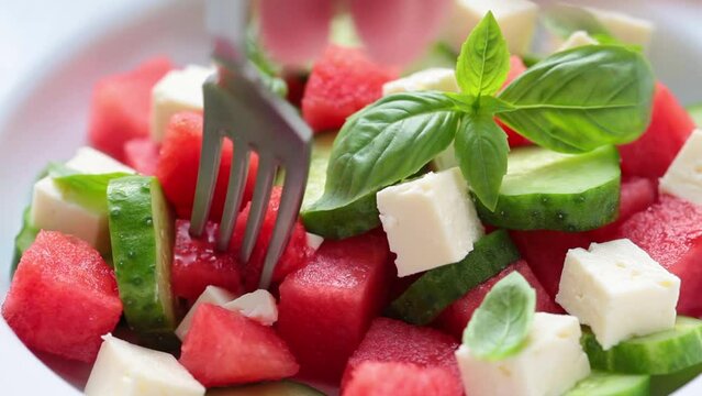 Watermelon salad with feta cheese, cucumber and basil in plate, close-up. Summer recipe, healthy diet, detox food.