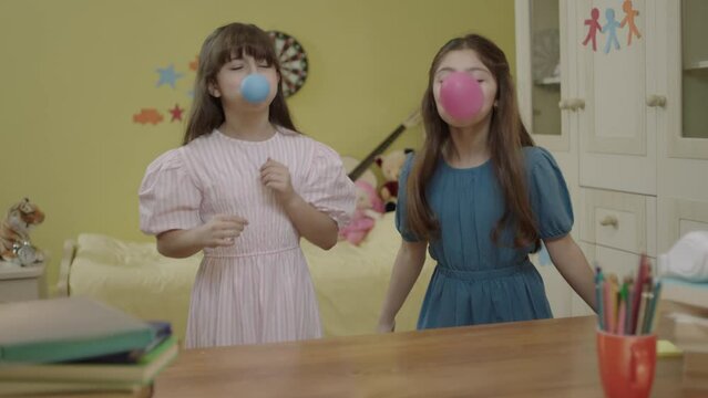 Little girls are blowing air into the balloon. Happy birthday party, celebration. Children are having fun by inflating balloons in their rooms. Cute kids inflate the balloon for their birthday.