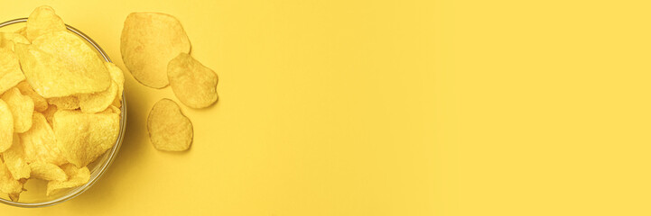 Potato chips in a round bowl on a yellow background. Space for text on the left. Top view. The most popular snack. Junk food. Banner with free space for text