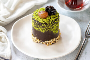 Pistachio and chestnut cake on a gray background. Chocolate covered cake with chestnut and cream inside. close up