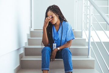 Worried and stressed doctor sitting on corridor. Shot of a female nurse suffering from a serious...
