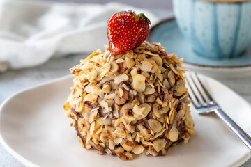 Hazelnut, strawberry and chocolate cake on gray background. Fruit and cream cake covered with chocolate on the outside. close up