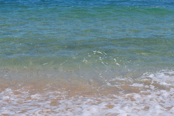 Clear emerald green sea with white foam