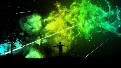 A man standing on the grass on a hill with a tree, admires the starry sky with a beautiful yellow-green nebula and falling meteors. The concept of the beauty of nature and the universe.