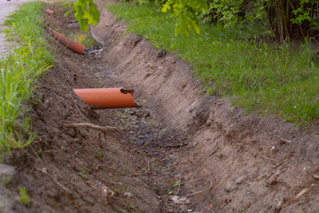 sewer pipes sticking out of the ground above a trench dug for sewage drains rainwater drains photo taken in summer in warm weather during the day