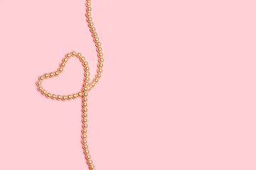 Collar de perlas sobre un fondo rosa pastel liso y aislado. Vista superior y de cerca. Copy space