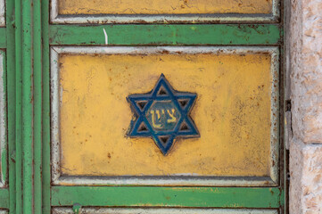 A blue star of David with the Hebrew word Zion in the center on a colorful, painted, metal door in Jerusalem.