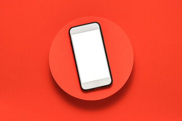 Blank screen mobile phone with clipping path on the red podium top view. Mobile with copy space, sales and black friday concept