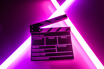 Clapperboard movie slate on Glowing neon lighting background. video director making cinema film....