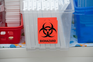 Medical waste bin with biohazard sign in hospital. Biohazardous containers used to safely remove sharps, needles, and IV catheters that contain any human blood.