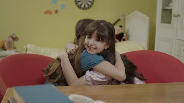 Laughing little girls spending time together in the nursery at home. Best friends hug, children hug each other Real ages, friends of all sizes. Playing, happy childhood, positive emotions, true feelin