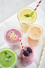 Smoothie variation - blueberry, banana, orange, spinach, oats. Range of smoothies on a white background