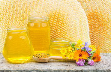 Three jars with honey on the background of beehives with copy space