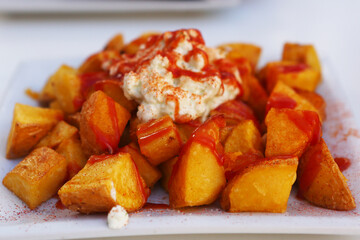baked potato with garlic sauce aioli and tomato ketchup on square plate with human hands closeup photo