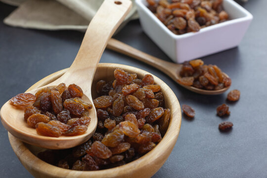 Pasas en un cuenco de madera y pasas en una cuchara de madera