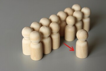 Selective focus image of one wooden doll leave the group. Refusal to participate, withdrawal in protest. Exit project, dismissal from work concept