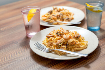 Dinner for two, pasta with mussels and water with lemon, close-up.