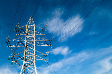 Electrical high voltage tower with wires on a cloudy blue sky background at sunny day