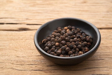 fragrant spices ,black peppercorn in black bowl on wood table
