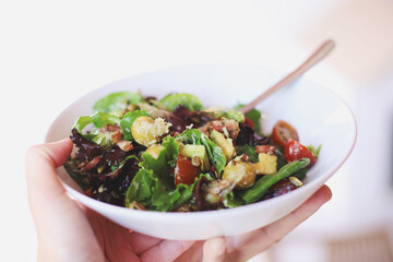 Hand holding a bowl of healthy salad