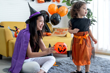 Asian mother and little child girl in Halloween costume playing on the floor in living room, Halloween concept