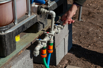 Hand opens tap on plastic irrigation system