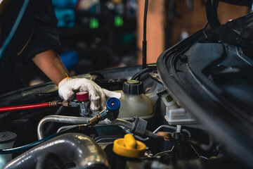 Mechanic tuning the manifold gauge to measure the pressure of the car air conditioner. - obrazy, fototapety, plakaty