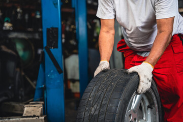 Asian male mechanic wearing gloves checking wheels and tires.