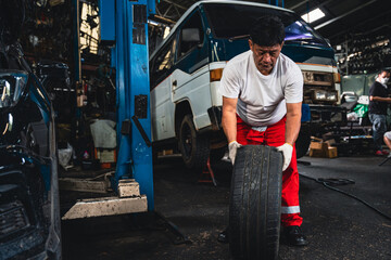 Fototapeta na wymiar Asian male mechanic wearing gloves checking wheels and tires.