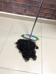 Human hair after cutting on the floor of a barber shop. Hairdresser sweeping hair clippings on floor in beauty salon stock photo