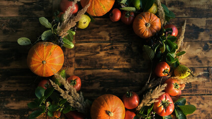 Round frame made of autumn vegetables and fruits on wooden background.