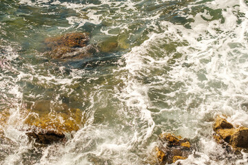Sea waves breaking on rocks and hitting the shore.