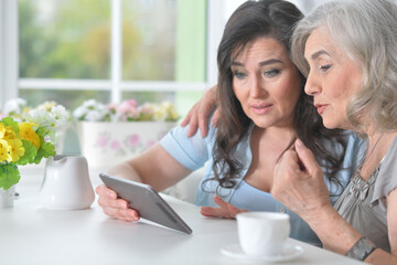 Two mature women using modern tablet