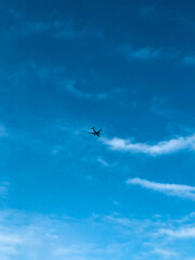 A plane in the middle of a blue and cloudy sky