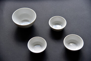 White porcelain salad bowls on a black background. Beautiful four white saucers on black.