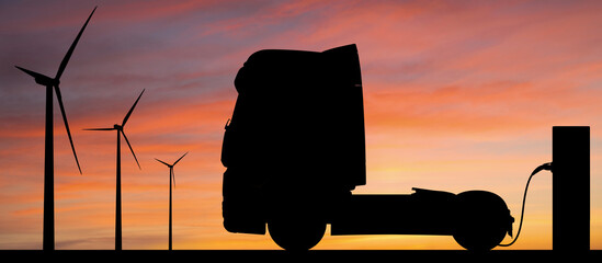 Silhouettes of charging electric truck and wind turbines. Getting electricity from renewable energy...