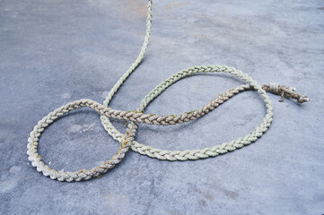 Metal background and texture of a long old hemp twisted rope in an infinite loop shape. Wallpaper gray.