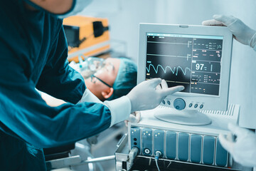 Two professional surgeon doctor perform surgery operation look at Electrocardiogram monitor show...