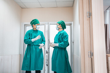 Two confidence doctor wear protective scrub suit with glove,medical mask talk,discuss patient health in hospital corridor,hallway. Professional team surgeons. Healthcare,Hospital emergency concept