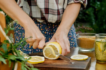 Female hands making summer lemonade beverage outdoors.