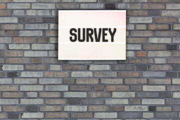 Survey message in light box on brick wall