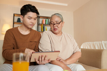 Man Installing Applications on Tablet of Grandmother