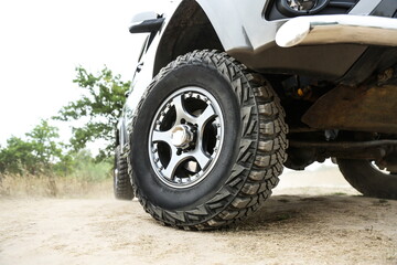 Fototapeta na wymiar SUV wheel close up is on nature background in summer. mud tire close up is on off road car. 