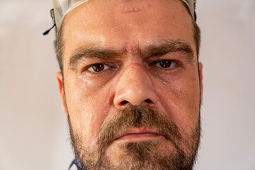 Sweaty, exhausted man face with safety equipment marks.