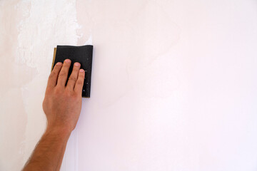 Man hand rubbing wall with sandpaper. There is title blank.