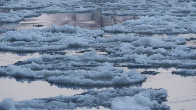 White ice floats on the river in winter close-up.