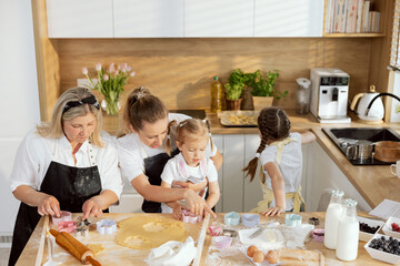 Happy family spending time together in modern kitchen baking cooking homemade cookies. Grandmother...