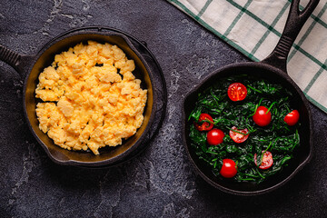 Cooked omelet and spinach with tomatoes in pans