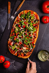 Homemade vegan pizza with tomatoes, peppers, olives, onions and herbs.