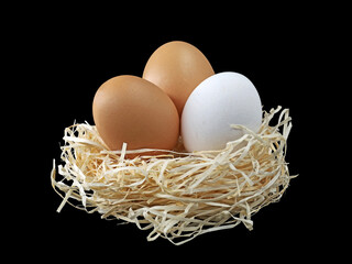 three eggs with wood wool isolated on black background